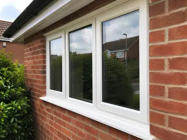 Clean white-framed window on a red brick home