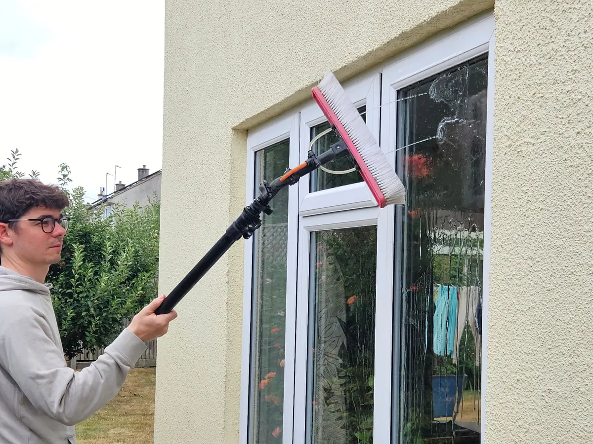 Ben cleaning white-framed windows with a pure-water brush